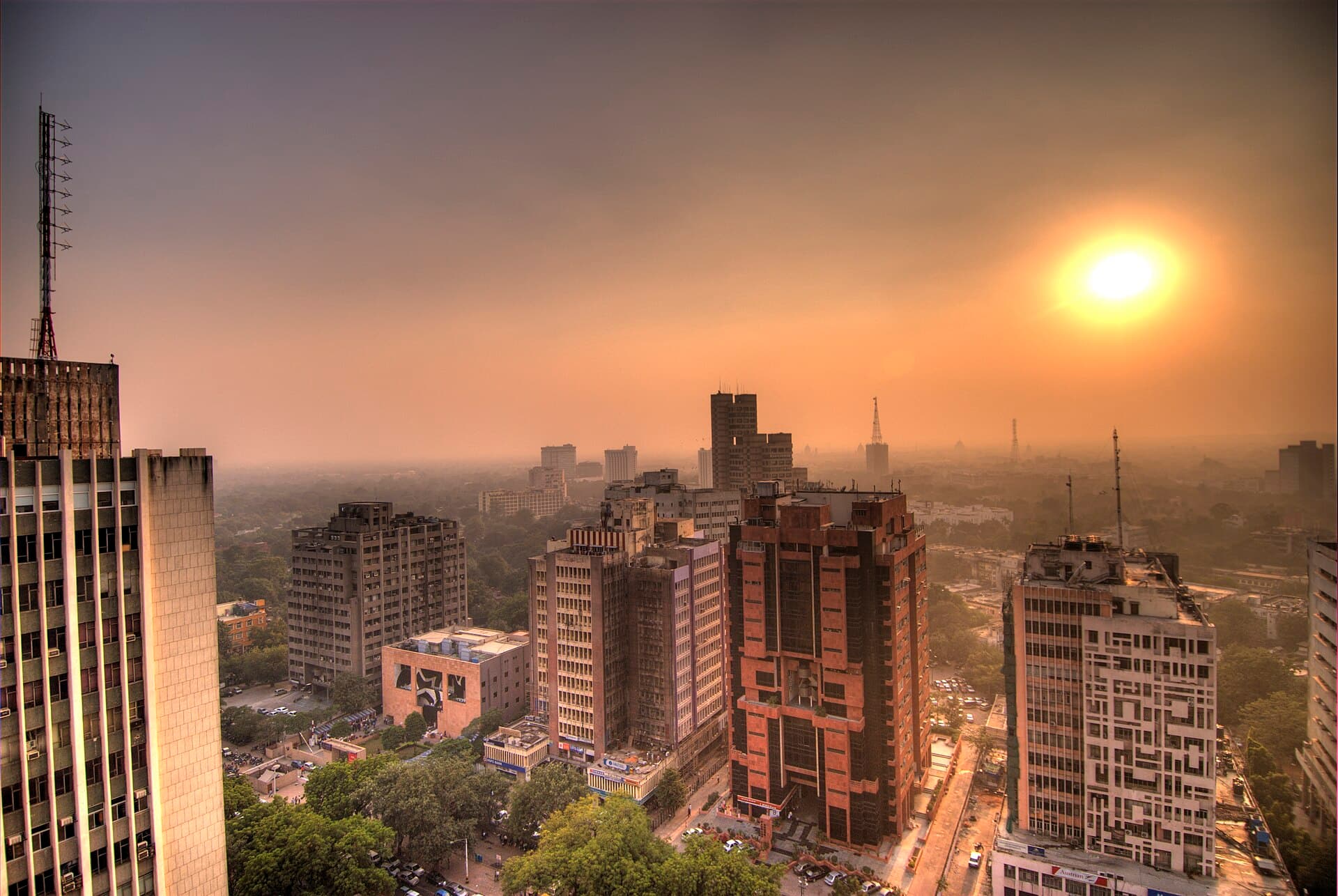 Office towers around Connaught Place, New Delhi, seen from above at sunset with the city stretching into the haze